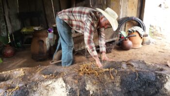 Don Luis Contreras filling the bottom pot of a clay potstill